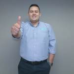Hombre sonriente con camisa azul haciendo el gesto de pulgar arriba atencion al cliente